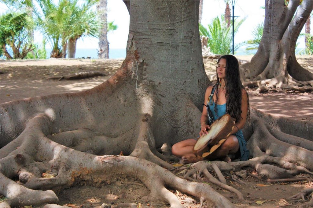 Cacao Ceremony with Stefanie Grace, playing the drum under the tree.