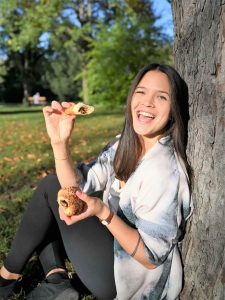 Stefanie Grace eating a croissant happily in the park