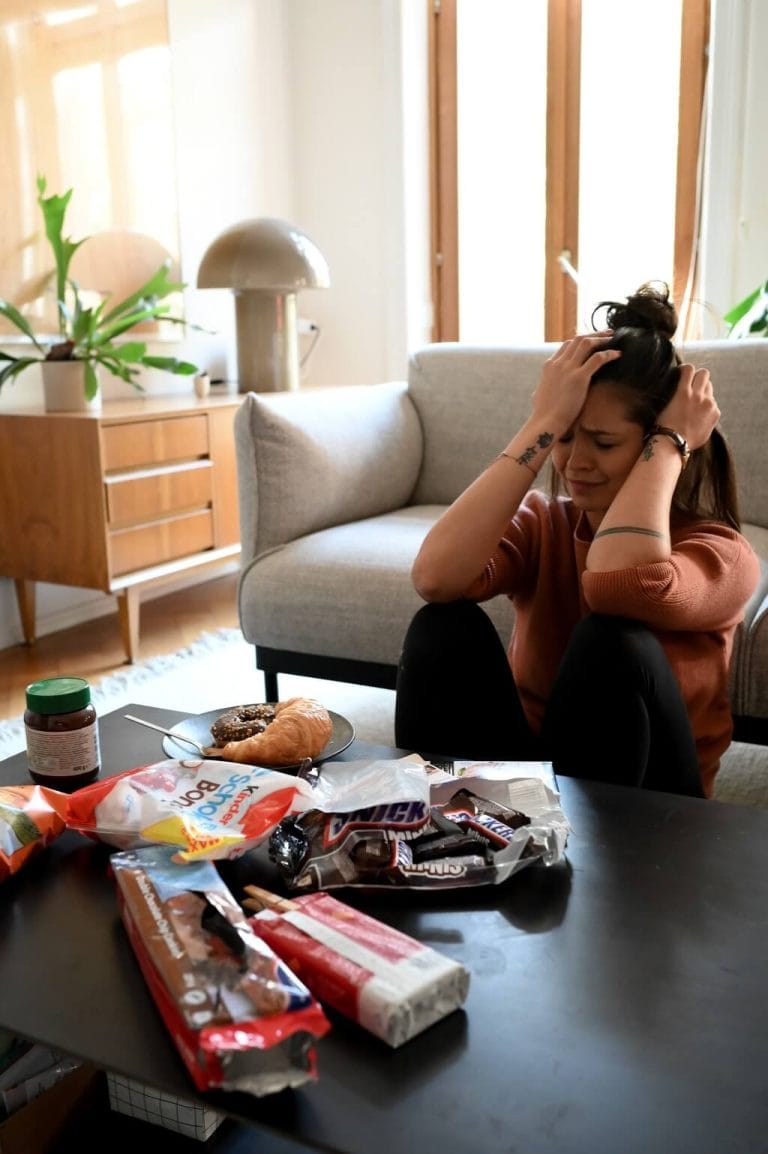 Frau sitzt vor einem grossen Berg Essen und ist verzweifelt
